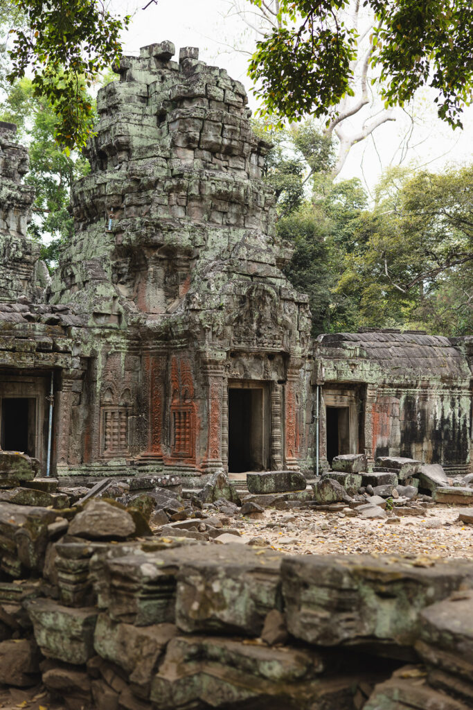 Ancient stone temple ruins covered in moss and vines, with weathered doorways and carvings among scattered stones and trees.